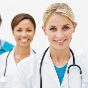 image1 Beautiful young doctor standing with hands folded and assistant doctors in background